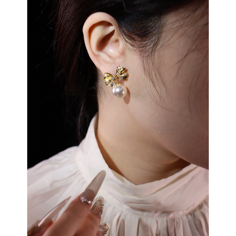 Gold pearl bow drop earrings by Yoshan